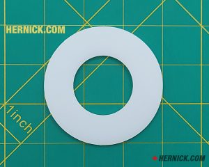 White sheave spacer/bearing for hydraulic cylinders on a green background with yellow grid markings.