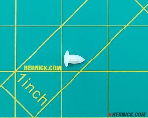 Small white wheel bumper with a compact rounded nib shape and short mounting stem on a green background with yellow grid marks.