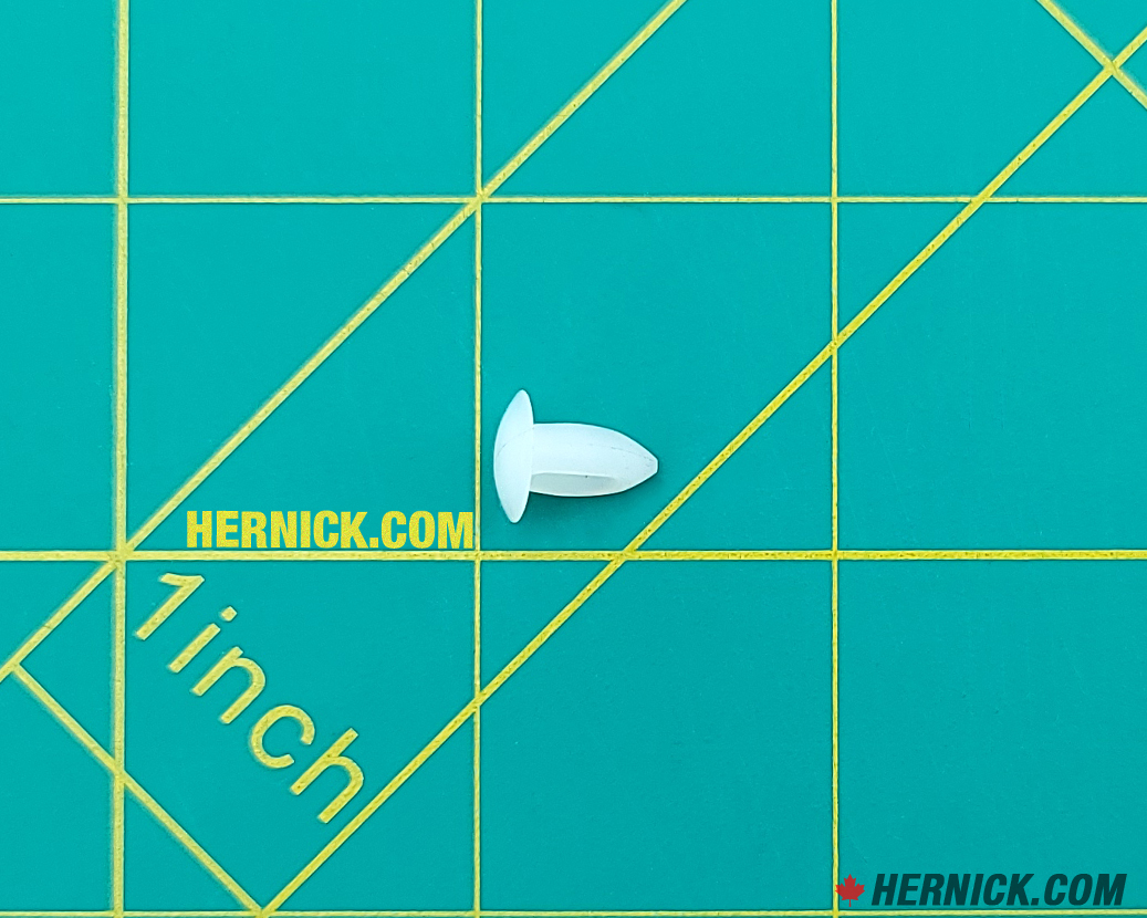 Small white wheel bumper with a compact rounded nib shape and short mounting stem on a green background with yellow grid marks.