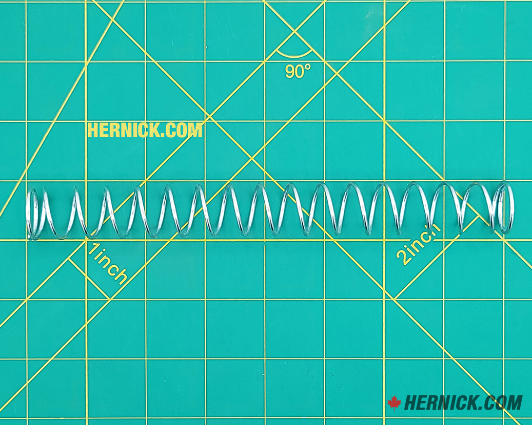 Heavy-duty steel arm restraint spring on a green background with yellow grid markings.
